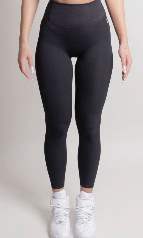 Person wearing black leggings and white sneakers on a plain background