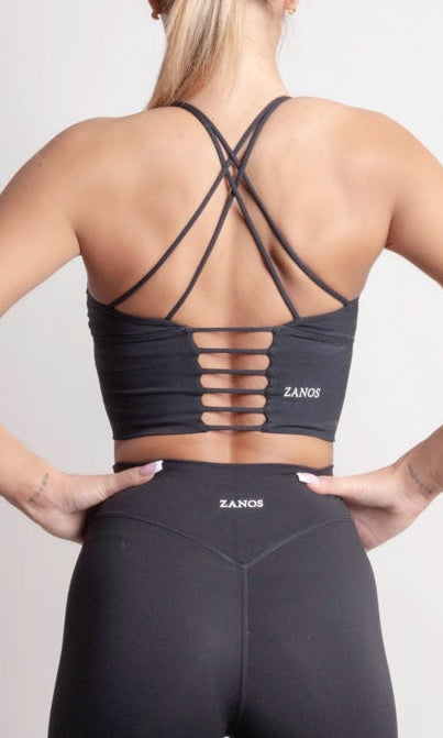 Back view of a woman wearing the NOIR Cross Top Black, showcasing its stylish cross-back design and comfortable fit.