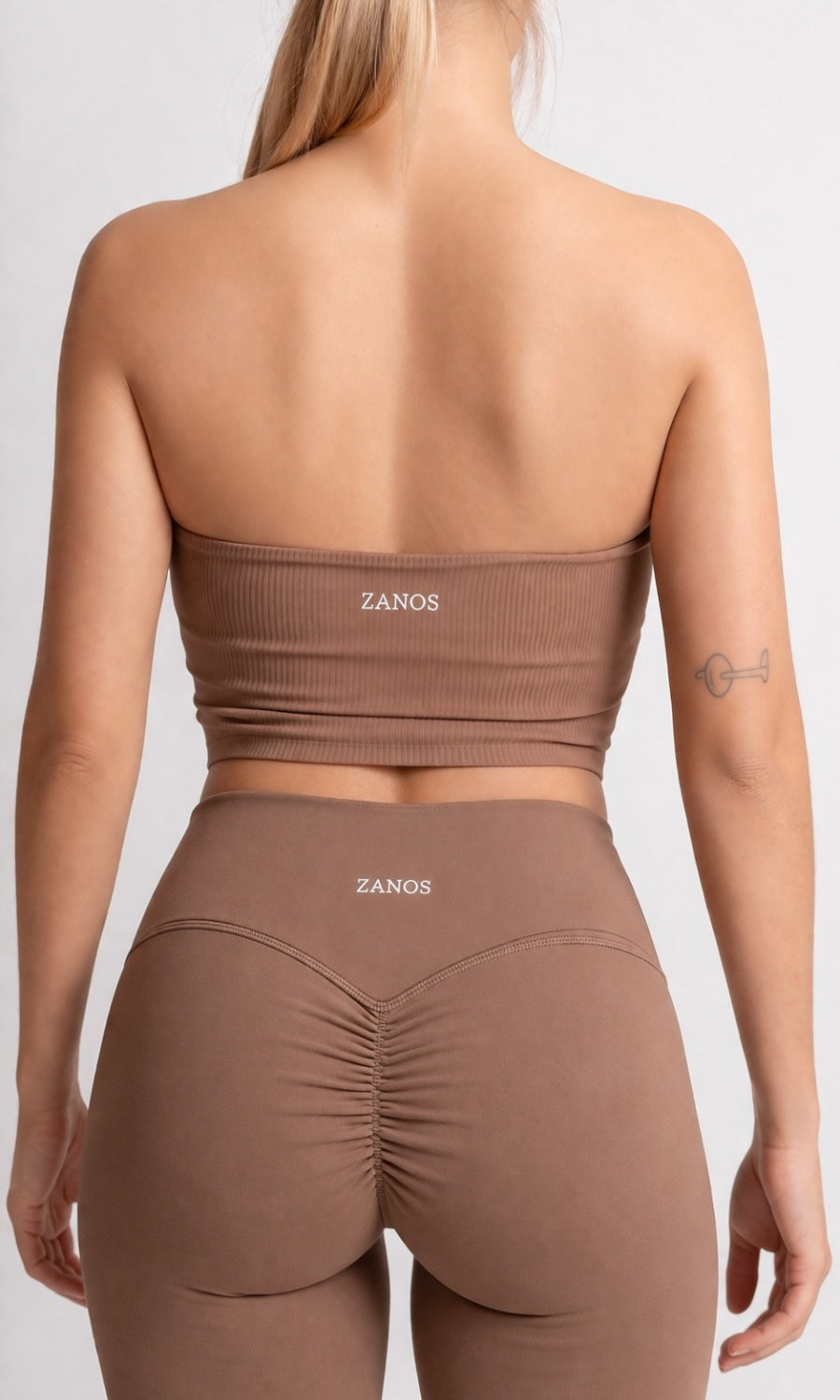 Person wearing a brown sports outfit with 'ZANOS' branding on a white background