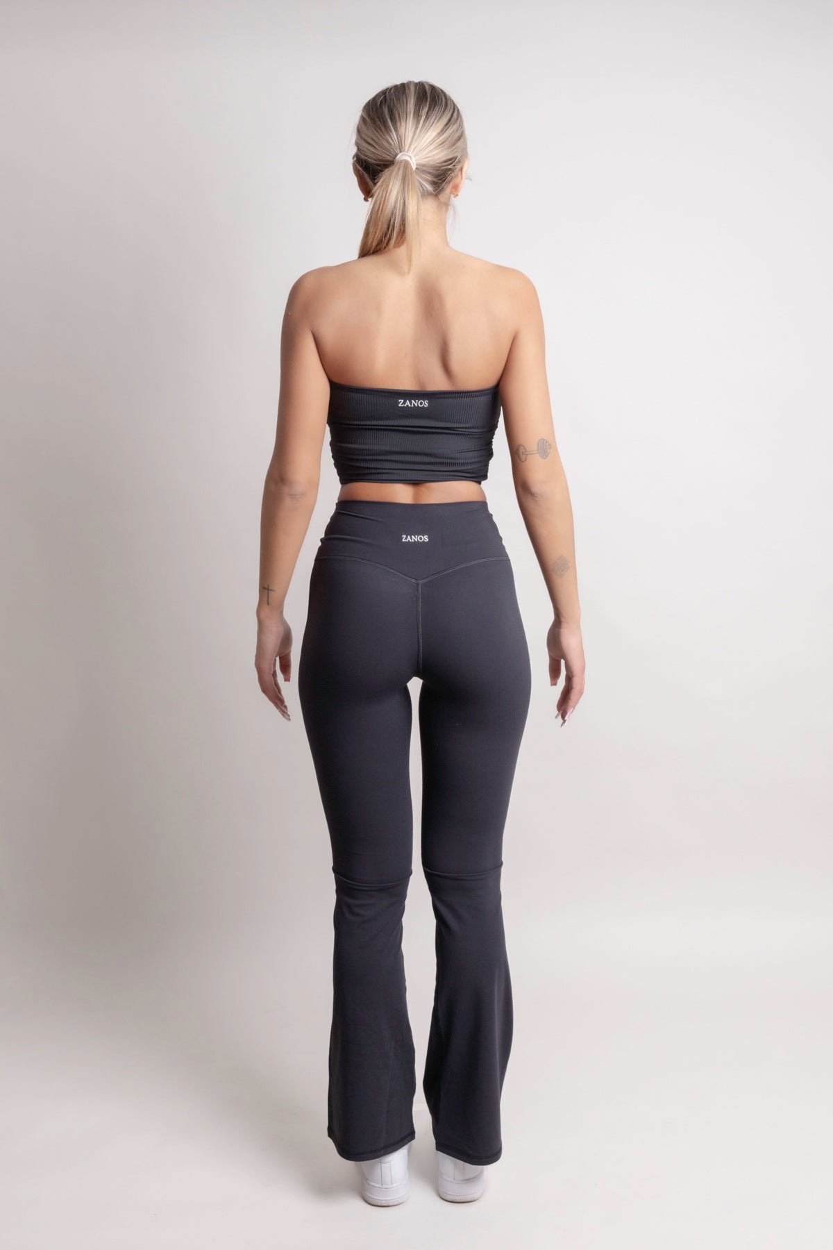 Person wearing a NOIR Bandeau Top black athletic outfit with visible branding on a white background