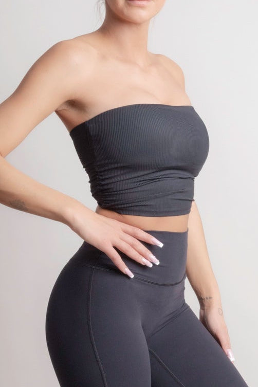 Woman wearing a NOIR Bandeau Top black outfit with a strapless top and flared pants on a plain background