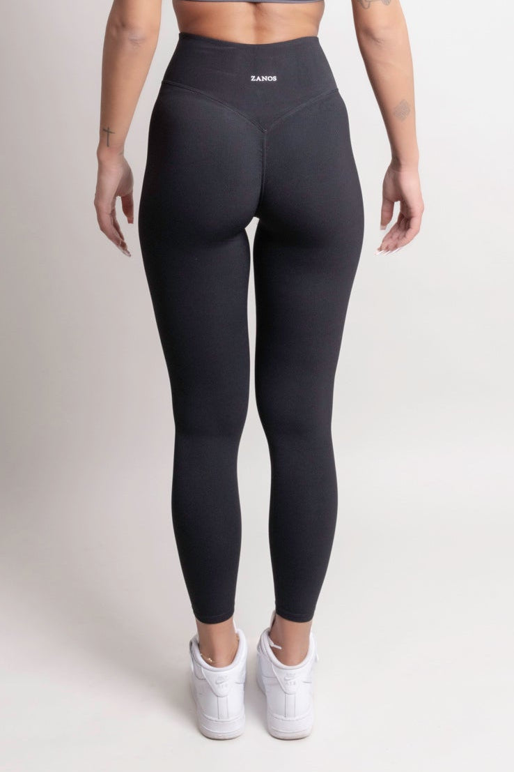 Model wearing NOIR CloudFit leggings black and a grey sports bra, showcasing the back view in a minimal setting.