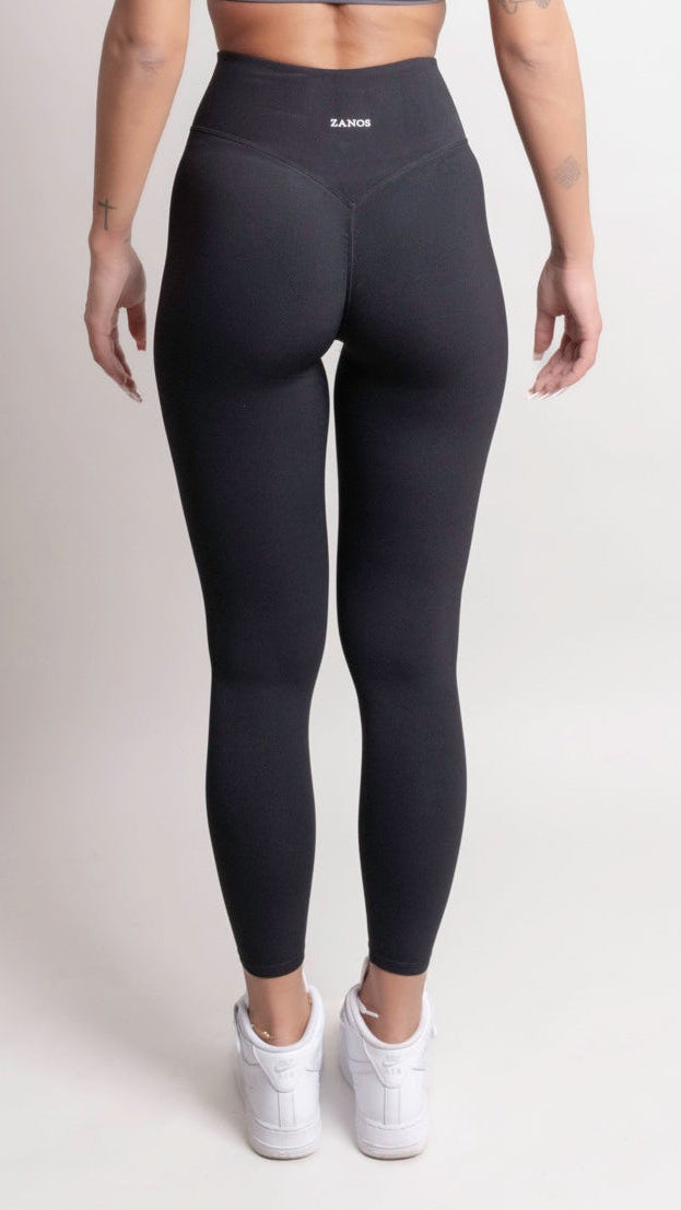 Model wearing NOIR CloudFit leggings black and a grey sports bra, showcasing the back view in a minimal setting.