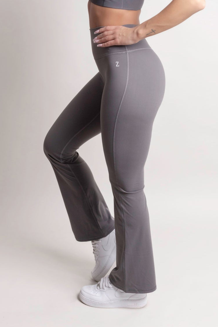 Model wearing NOIR Flare Pants Grey Women posing in a side profile, highlighting the stylish flared leg design.