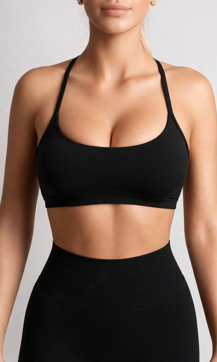 Person wearing a black sports bra and leggings on a light gray background