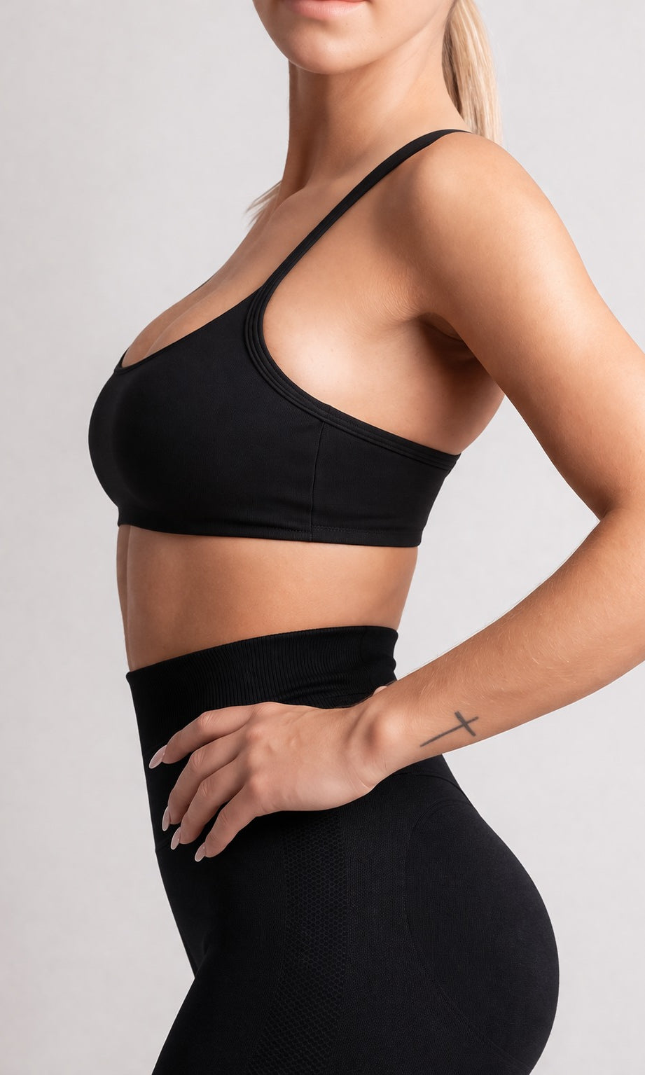 Person wearing a black sports bra and leggings on a light gray background