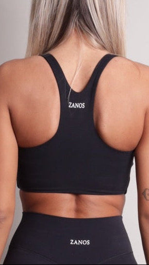 Person wearing a NOIR sculpt bra black sports bra and leggings with 'ZANOS' branding on a plain background