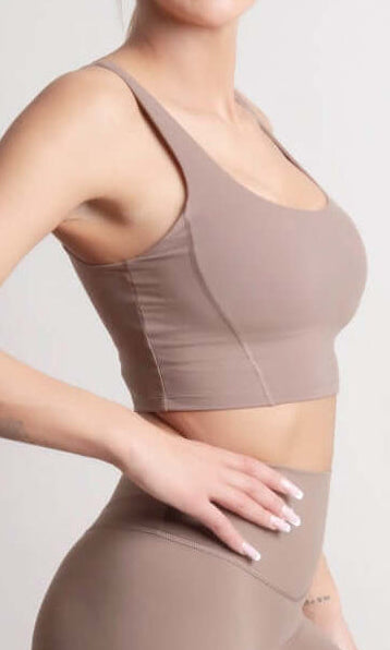Woman wearing NOIR Sport top a beige sports bra and leggings set on a light background