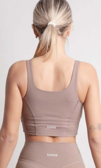 Person wearing NOIR Sport top a beige sports bra and leggings set on a white background