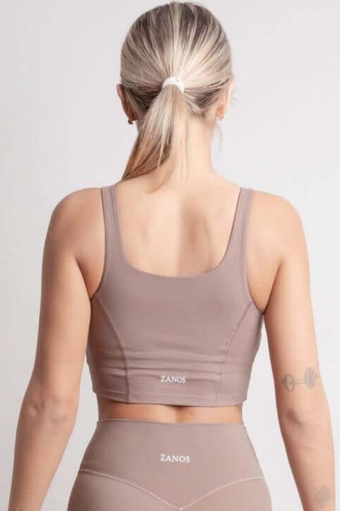 Person wearing NOIR Sport top a beige sports bra and leggings set on a white background
