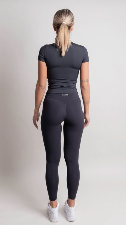 Person wearing a NOIR t-shirt black athletic outfit with 'ZANOS' branding on a light gray background