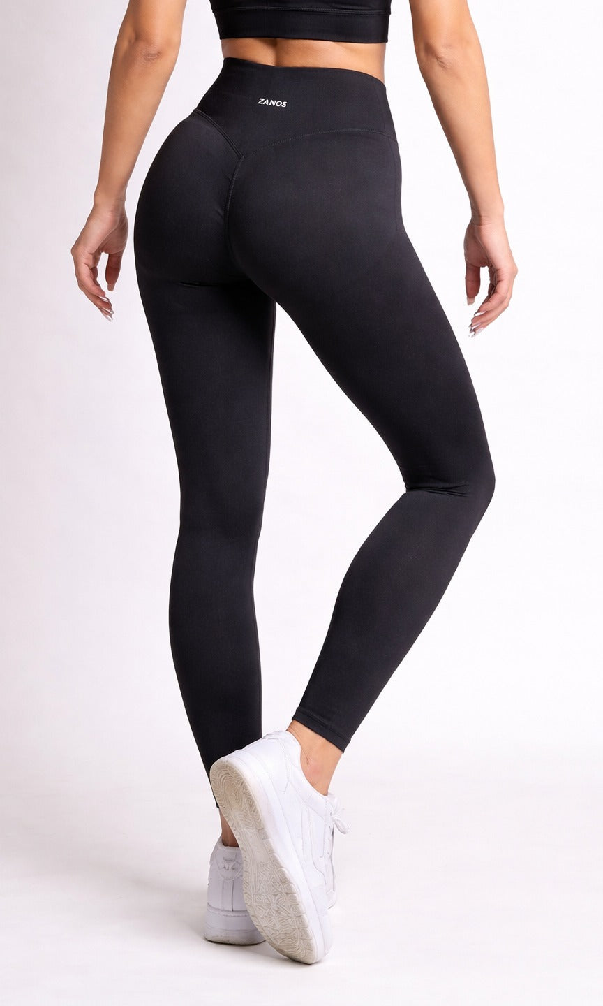Person wearing black leggings and white sneakers on a light gray background