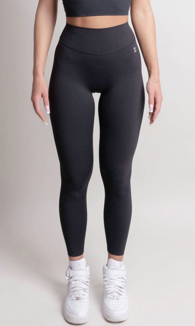Woman wearing a black athletic outfit on a plain background