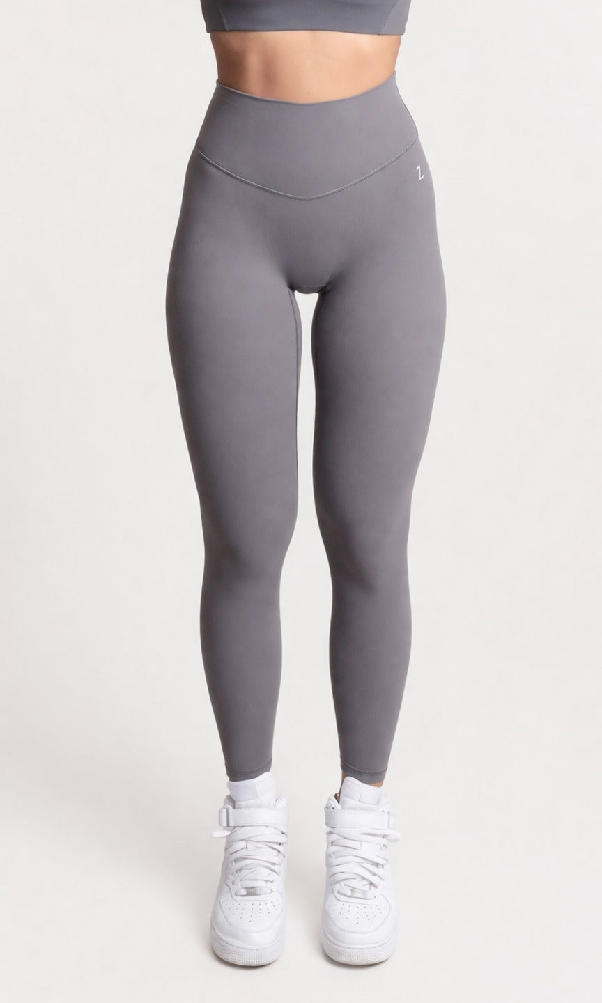 Woman wearing NOIR yoga leggings grey with matching sports bra, fron pose showcasing comfort and support.