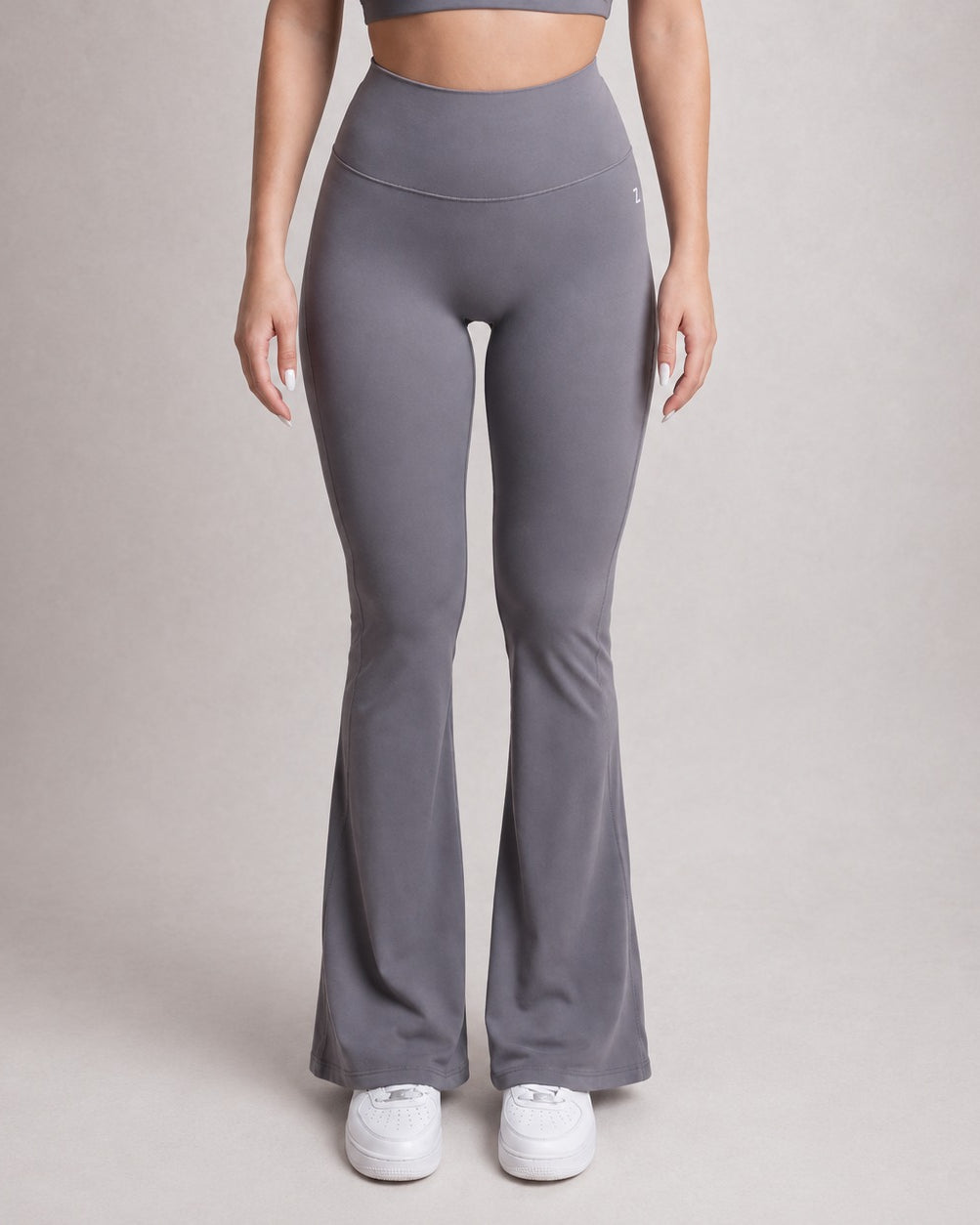 Person wearing gray flared leggings on a plain background