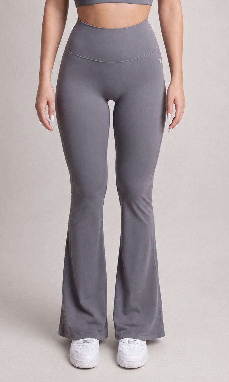Person wearing gray flared leggings on a plain background