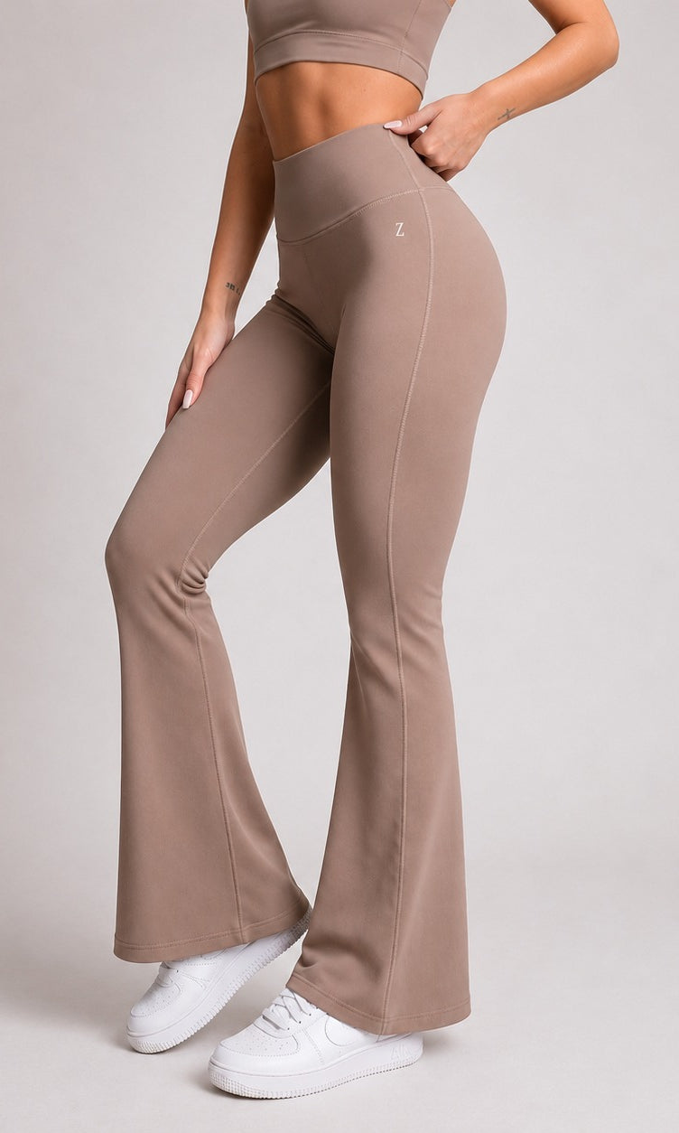 Person wearing brown flared pants and a matching top on a light gray background