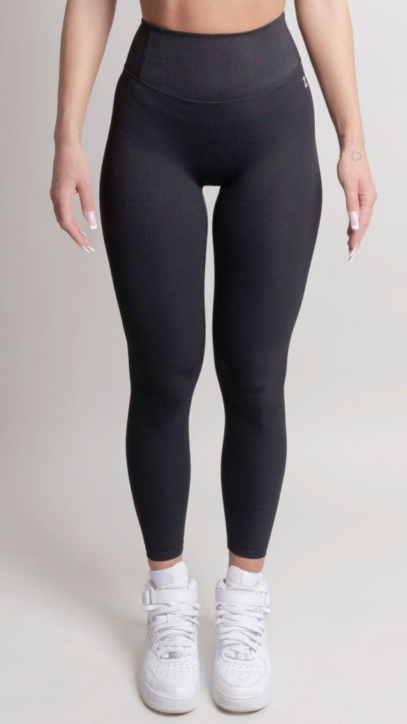 Person wearing black leggings and white sneakers on a plain background