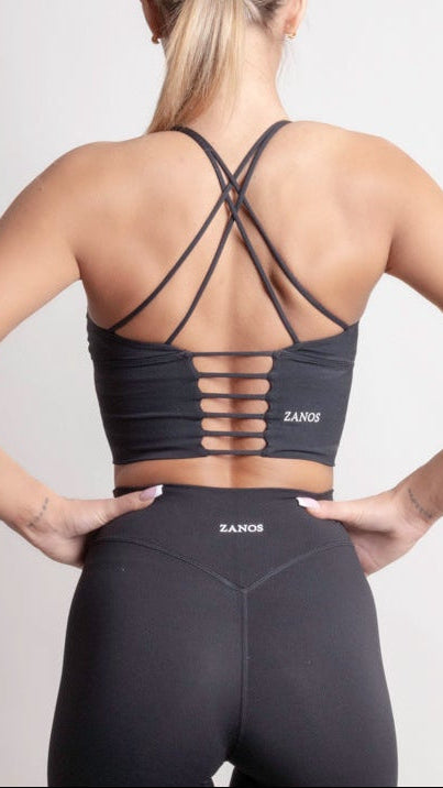 Back view of a woman wearing the NOIR Cross Top Black, showcasing its stylish cross-back design and comfortable fit.