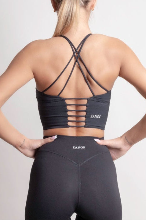 Back view of a woman wearing the NOIR Cross Top Black, showcasing its stylish cross-back design and comfortable fit.