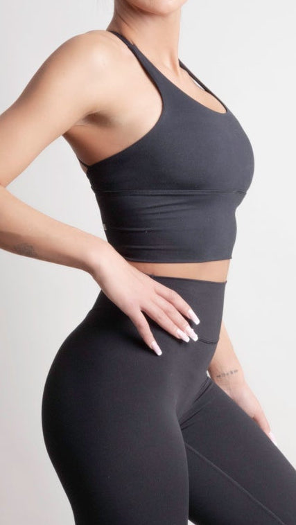 Model wearing NOIR Cross Top Black Women with leggings and sneakers, showcasing dynamic movement and comfort.