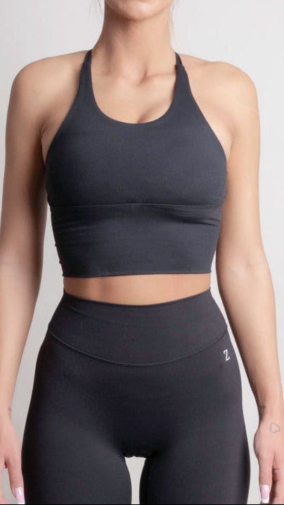 NOIR cross top black women model wearing a black sports top and high-waisted leggings, showcasing elegant design and comfort.