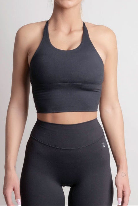 NOIR cross top black women model wearing a black sports top and high-waisted leggings, showcasing elegant design and comfort.