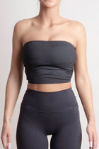 Person wearing a NOIR Bandeau Top black strapless top and leggings on a light gray background