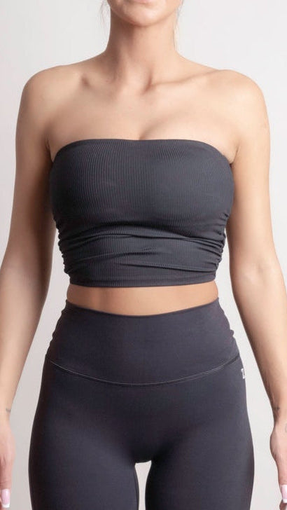 Person wearing a NOIR Bandeau Top black strapless top and leggings on a light gray background