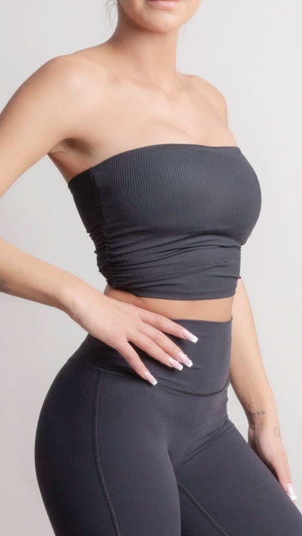 Woman wearing a NOIR Bandeau Top black outfit with a strapless top and flared pants on a plain background