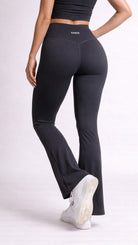 Person wearing black leggings with a visible brand logo on a white background