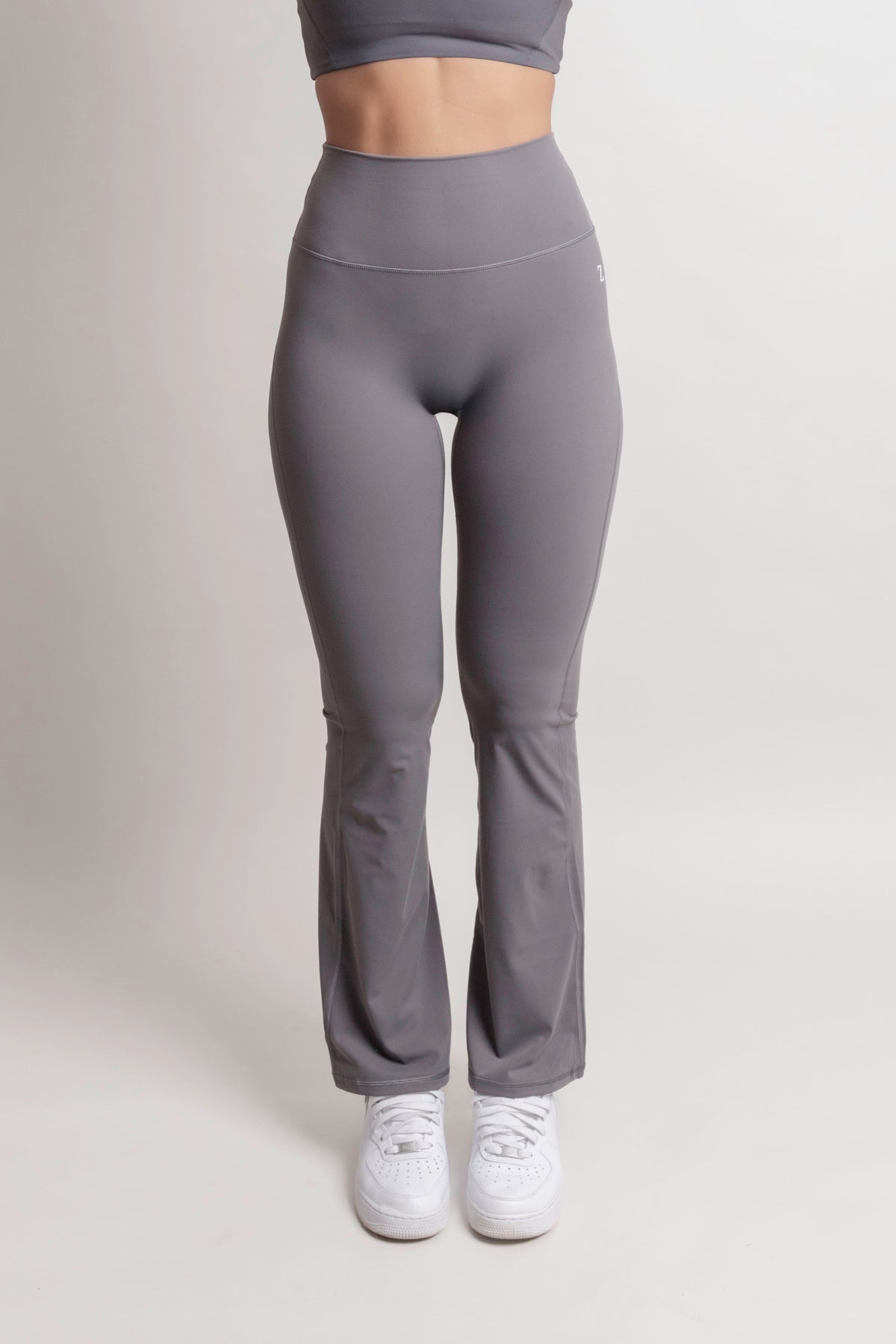 Model wearing NOIR Flare Pants Grey Women, high-waisted with a flared leg for an elongating silhouette.