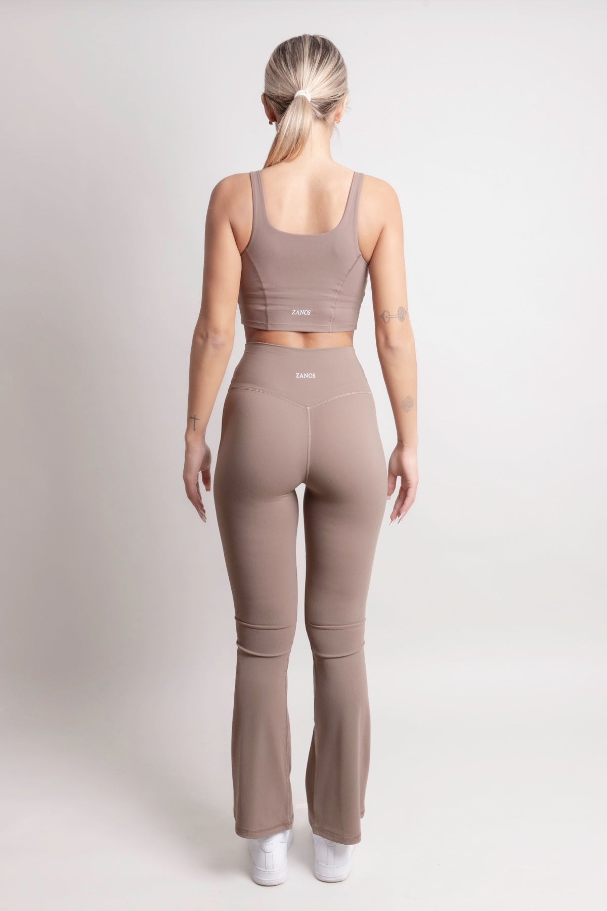 Model wearing NOIR Flare Pants Brown from ZANOS Apparel, showcasing the stylish high-waisted design and flared legs.