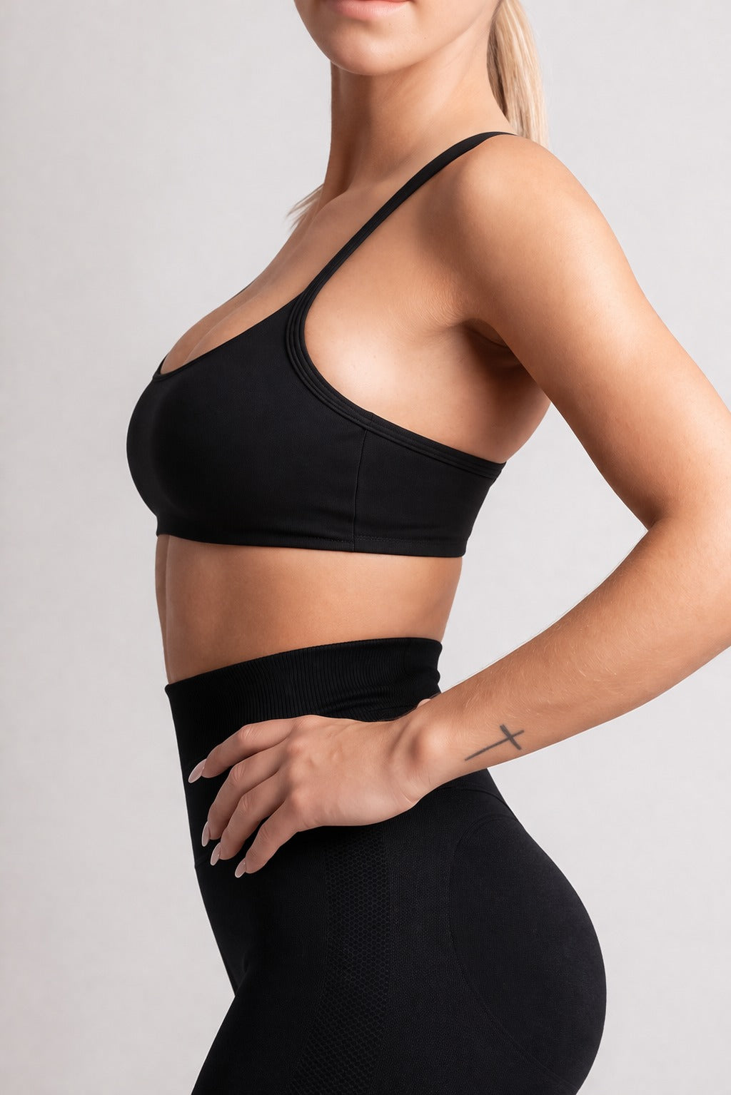 Person wearing a black sports bra and leggings on a light gray background