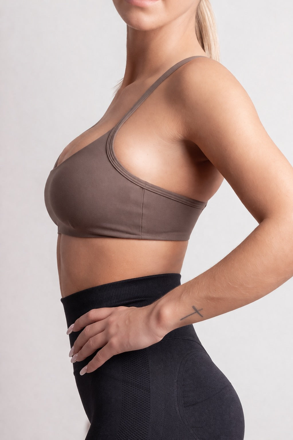 Person wearing a brown sports bra and black leggings on a plain background