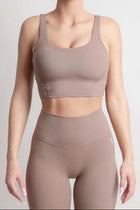 Woman wearing NOIR Sport top a beige sports bra and leggings set on a plain background