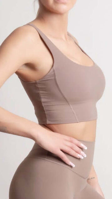 Woman wearing NOIR Sport top a beige sports bra and leggings set on a light background
