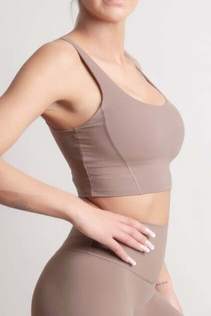 Woman wearing NOIR Sport top a beige sports bra and leggings set on a light background
