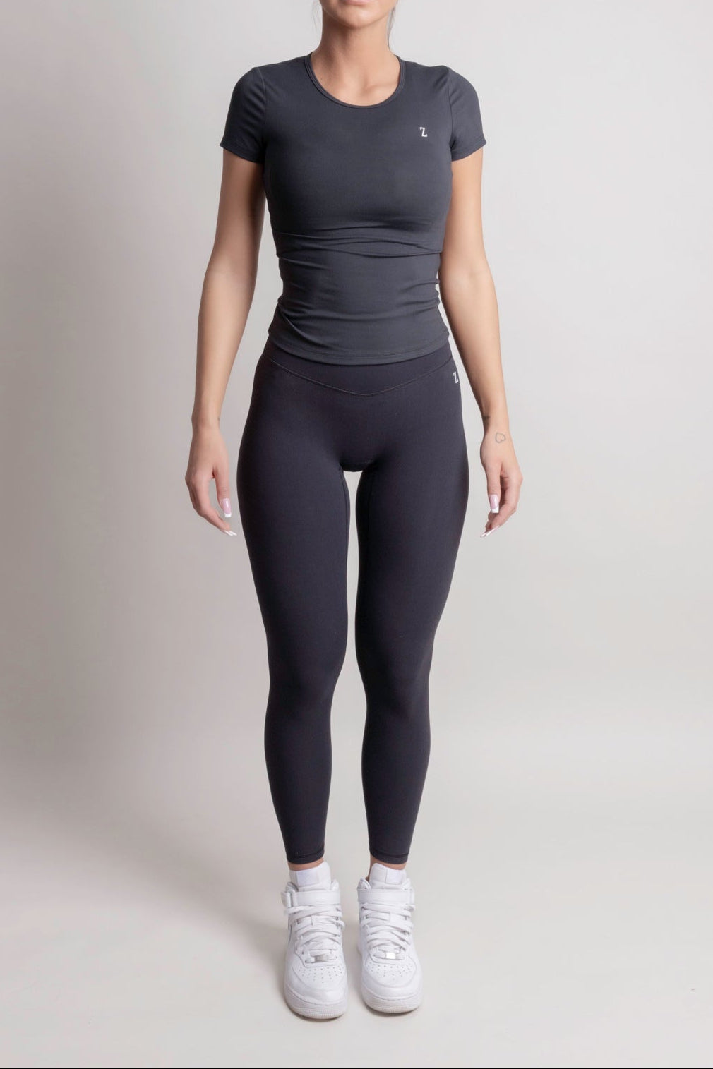 Person wearing a NOIR t-shirt Black t-shirt and leggings on a plain background