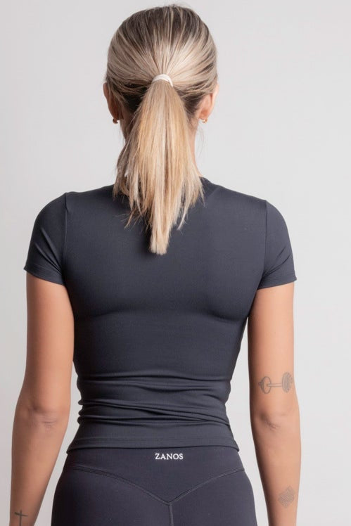 Person wearing a NOIR t-shirt black athletic outfit with 'ZANOS' branding on a light gray background