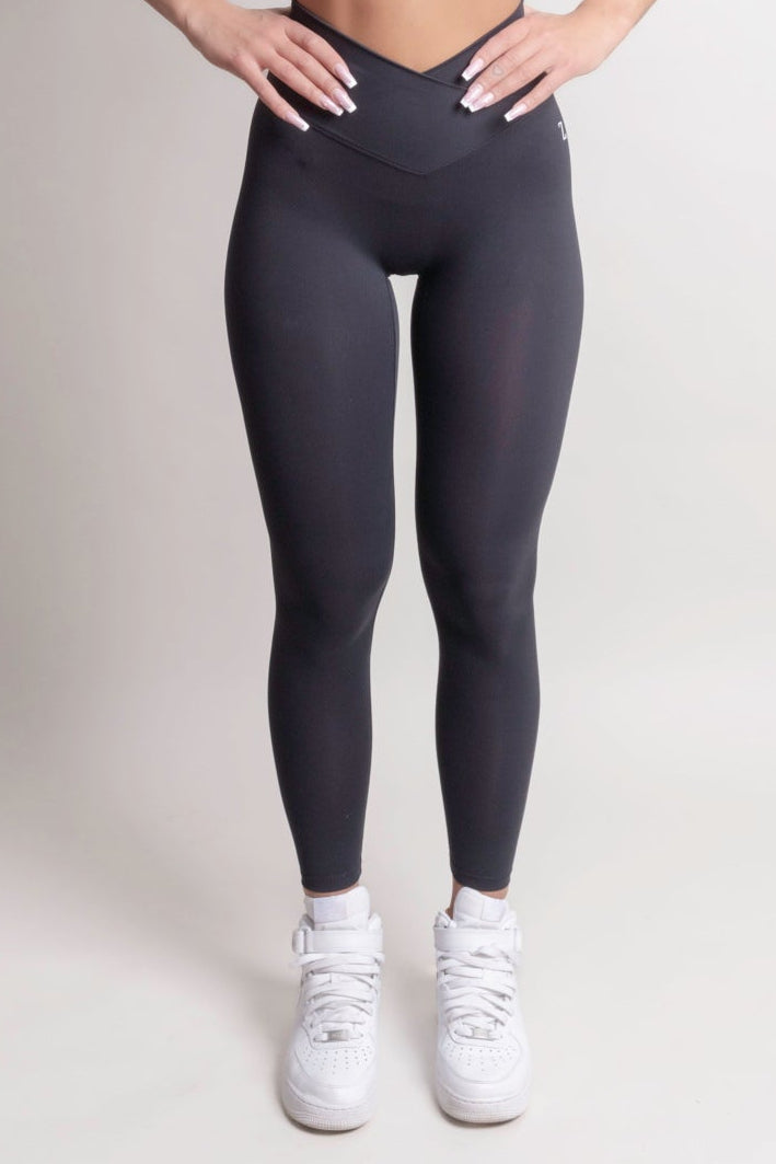 Woman wearing a sports bra and leggings on a plain background