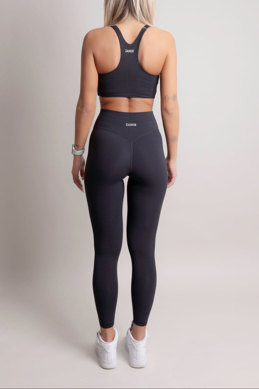 Person wearing a black sports bra and leggings set on a plain background