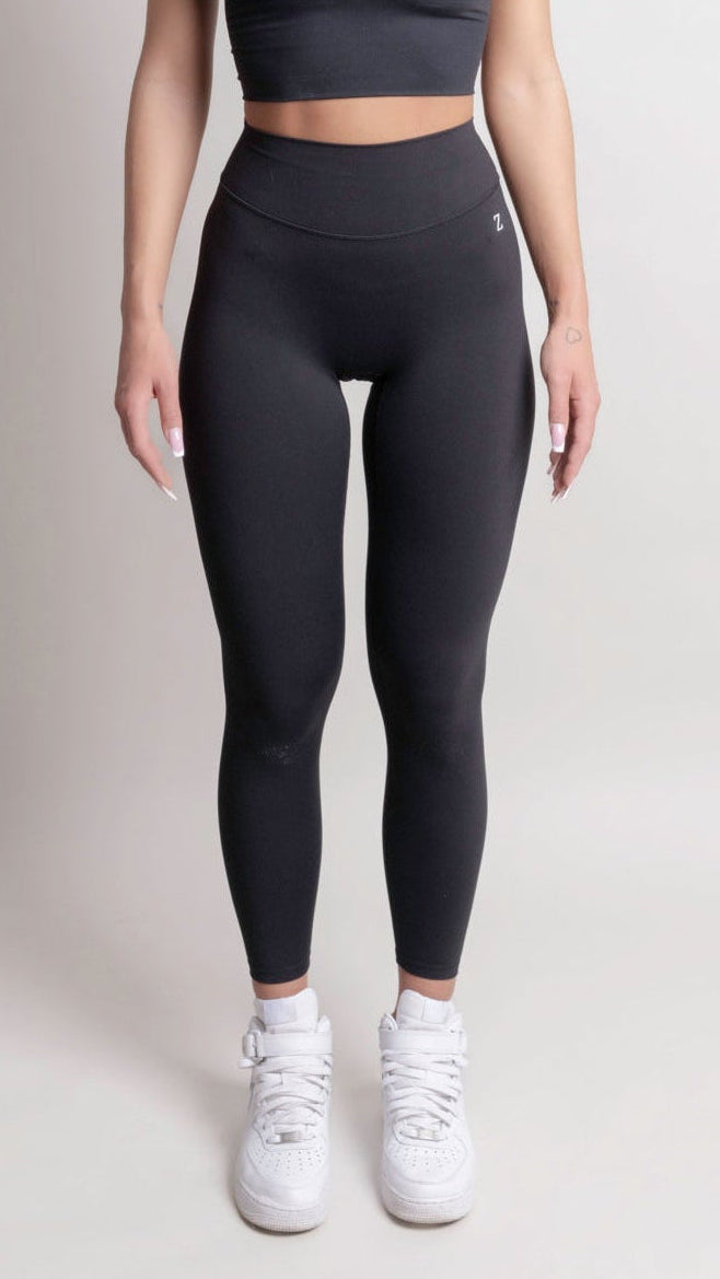 Woman wearing a black athletic outfit on a plain background