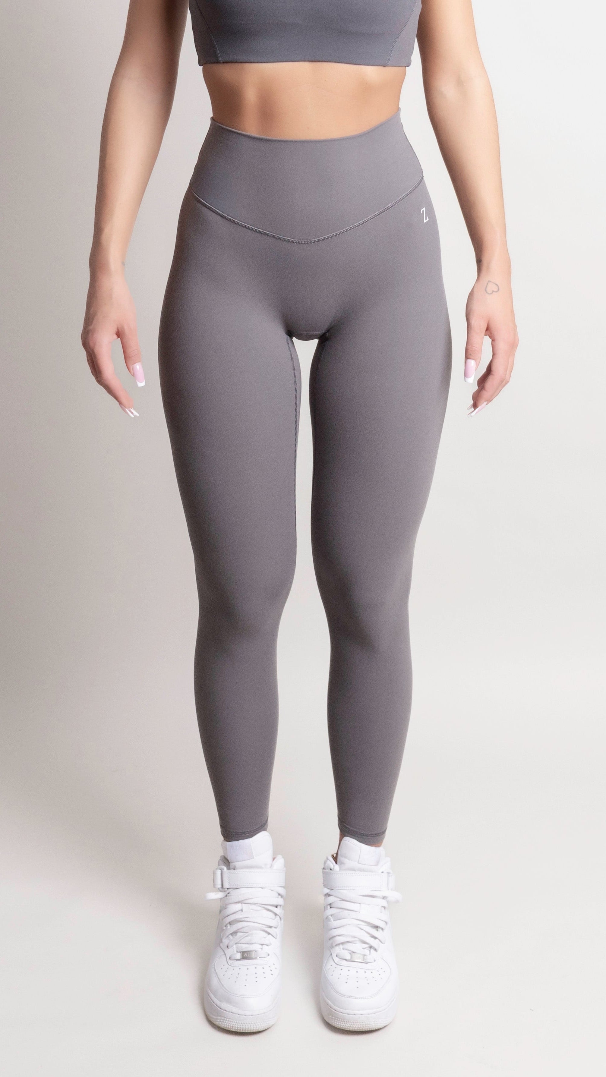 Model wearing NOIR yoga leggings grey paired with a crop top and white sneakers.