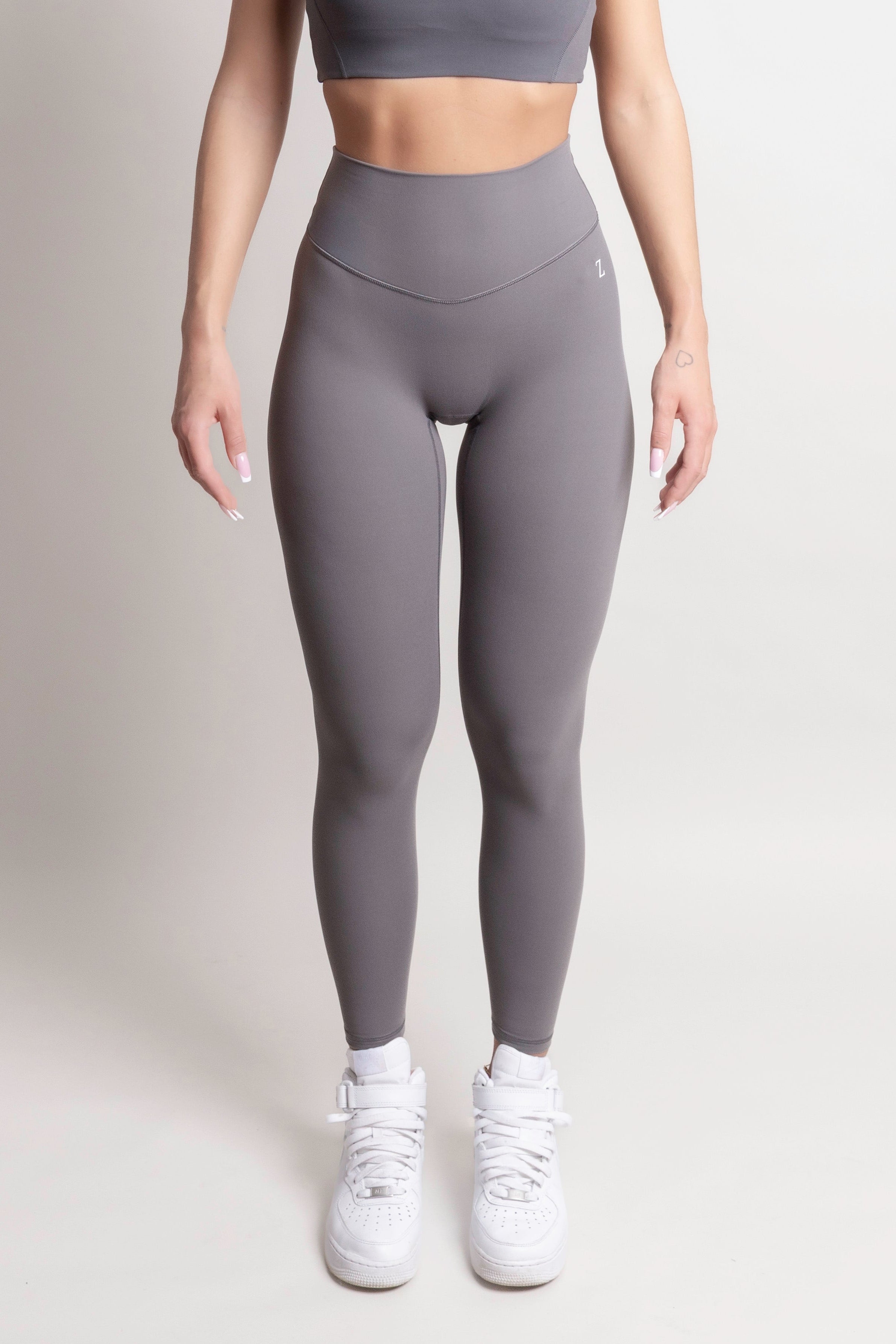 Model wearing NOIR yoga leggings grey paired with a crop top and white sneakers.