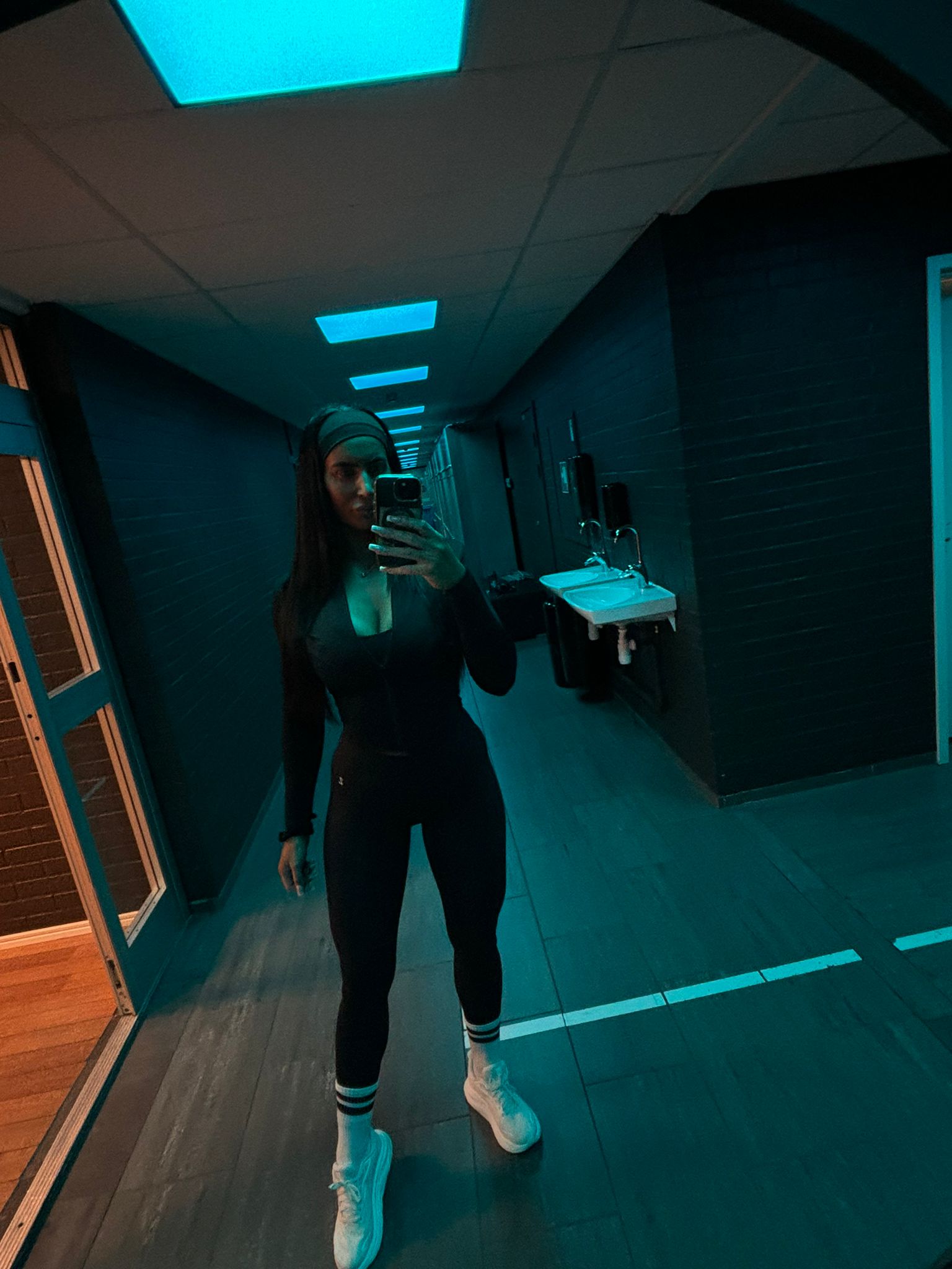 Person taking a mirror selfie in a dark room with blue lighting.