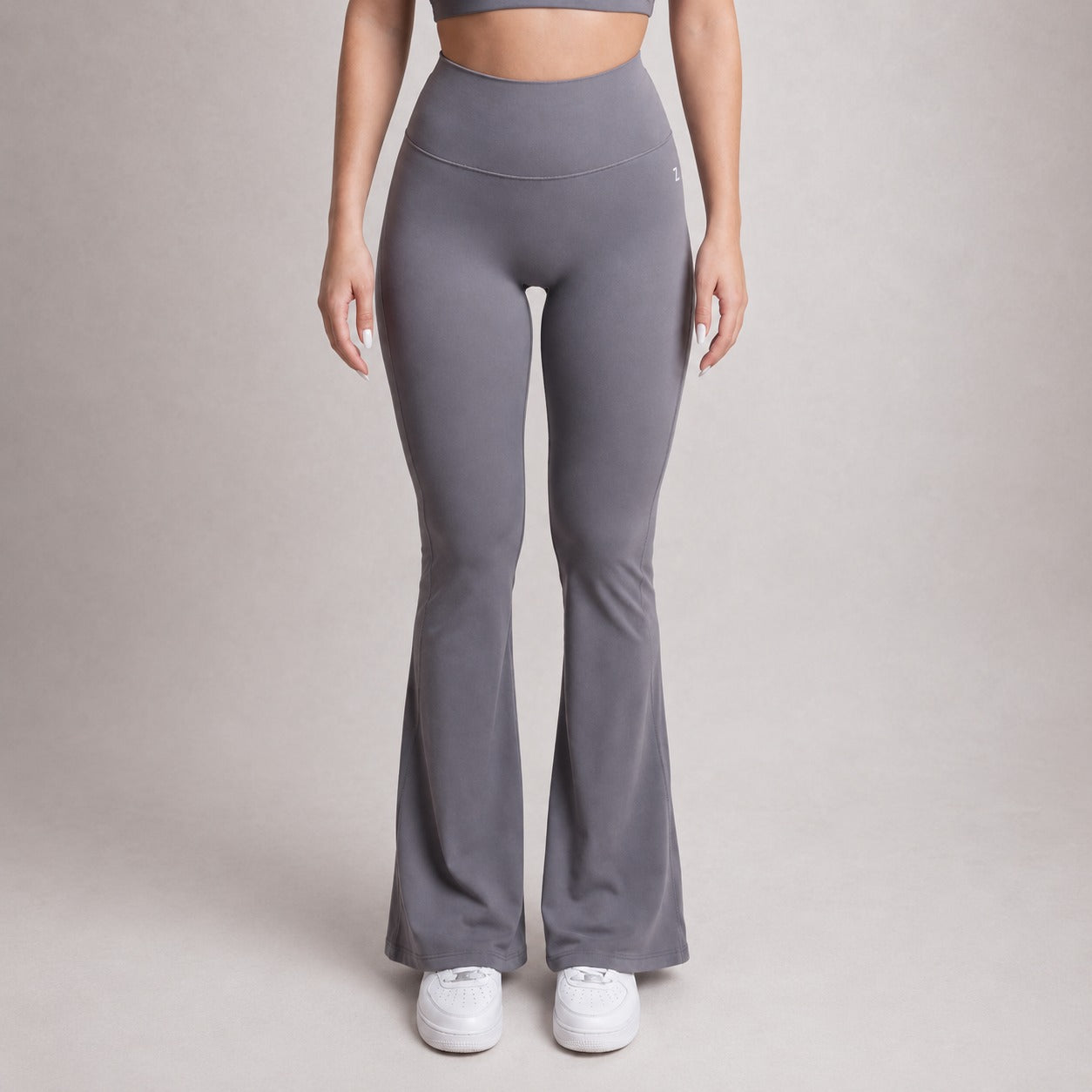 Person wearing gray flared leggings on a plain background