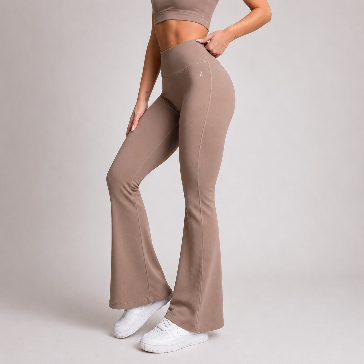 Person wearing brown flared pants and a matching top on a light gray background