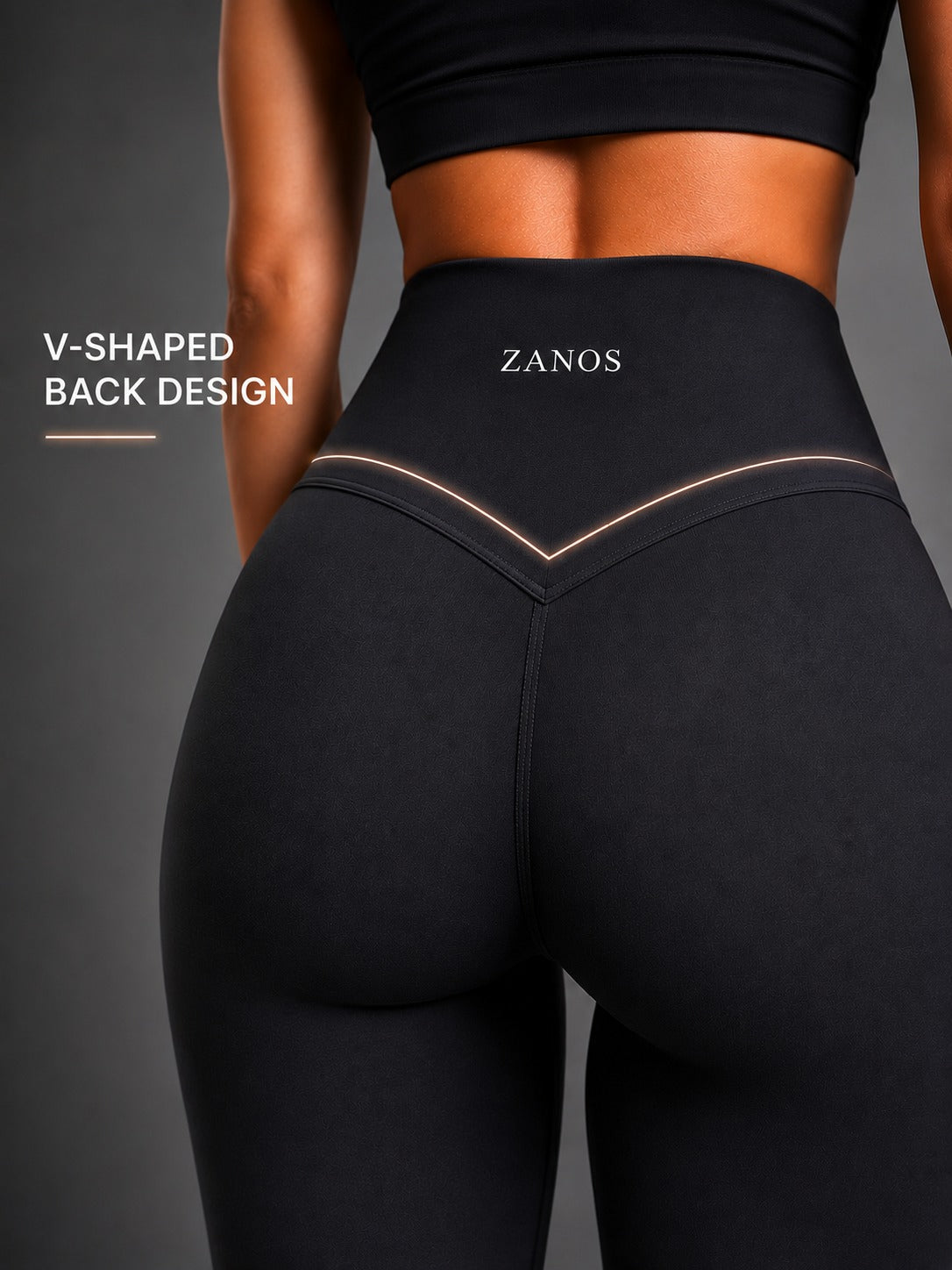 Close-up back view of a model wearing black high-waisted leggings with a V-shaped waistband design and the brand name ZANOS printed in white. White text on the left reads 'V-SHAPED BACK DESIGN'.